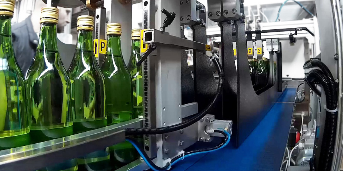 Green glass bottles with brass metal caps being sorted for packing.